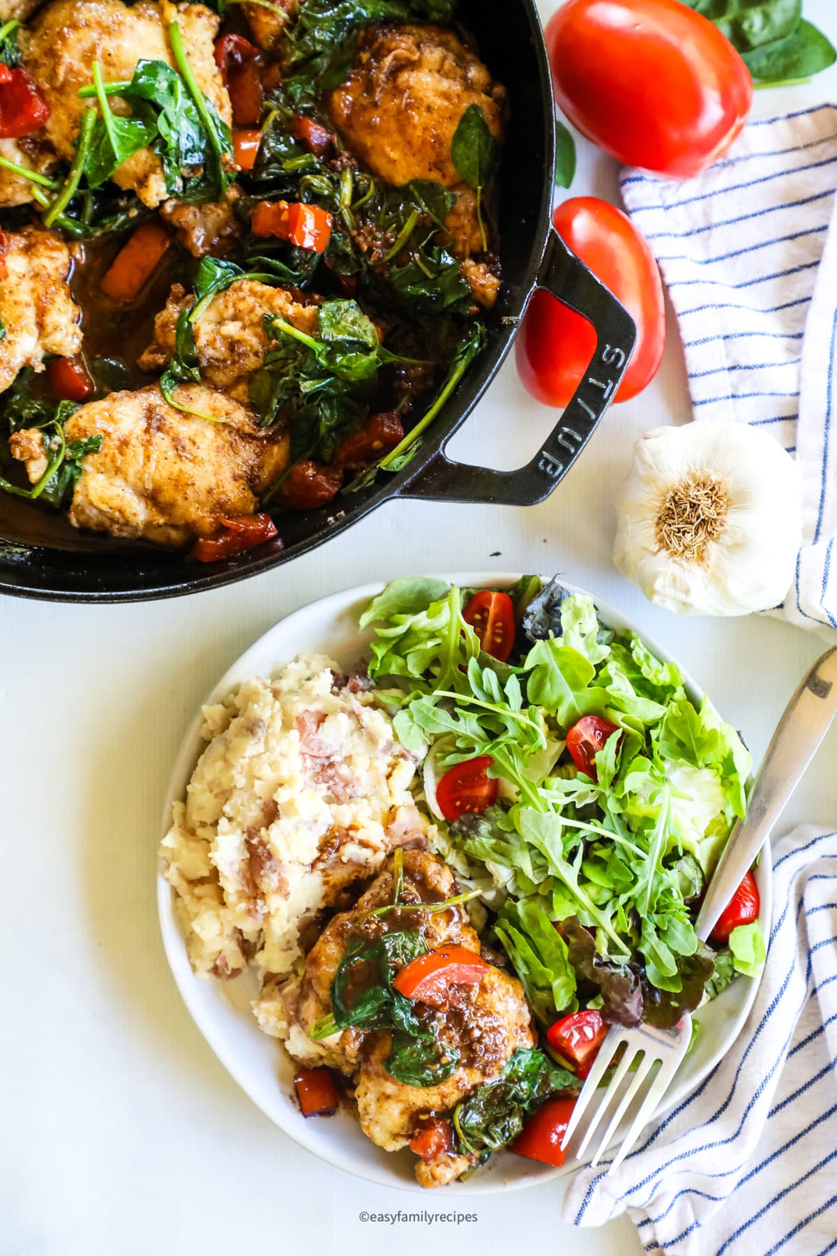 Overhead view of Tuscan skillet chicken thighs in pan and on plate with salad and potatoes