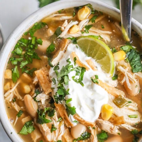 Closeup of Southwest white chicken chili in bowl with spoon and garnishes