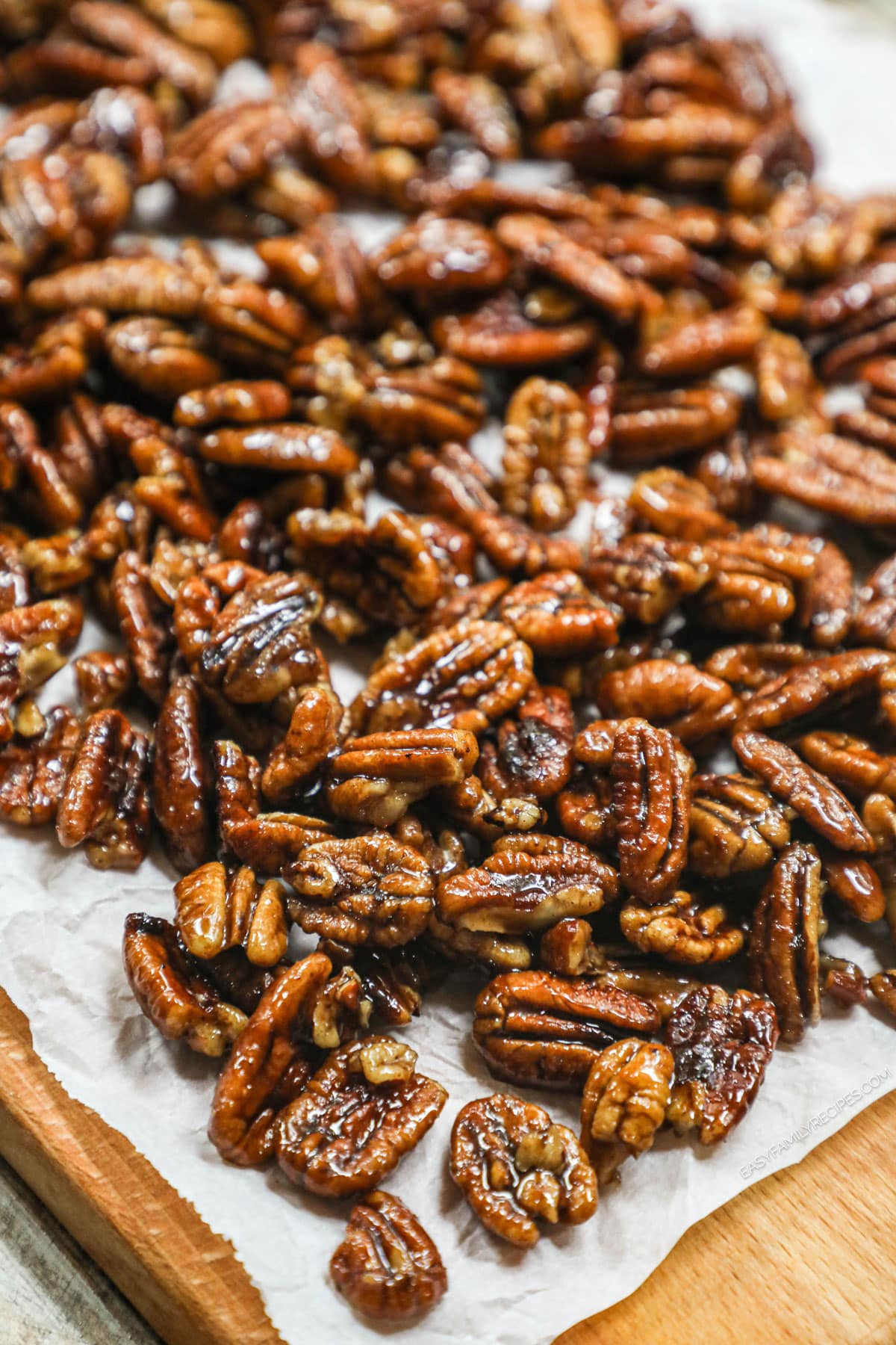 sweet and spicy pecans spread out on a piece of parchment paper.