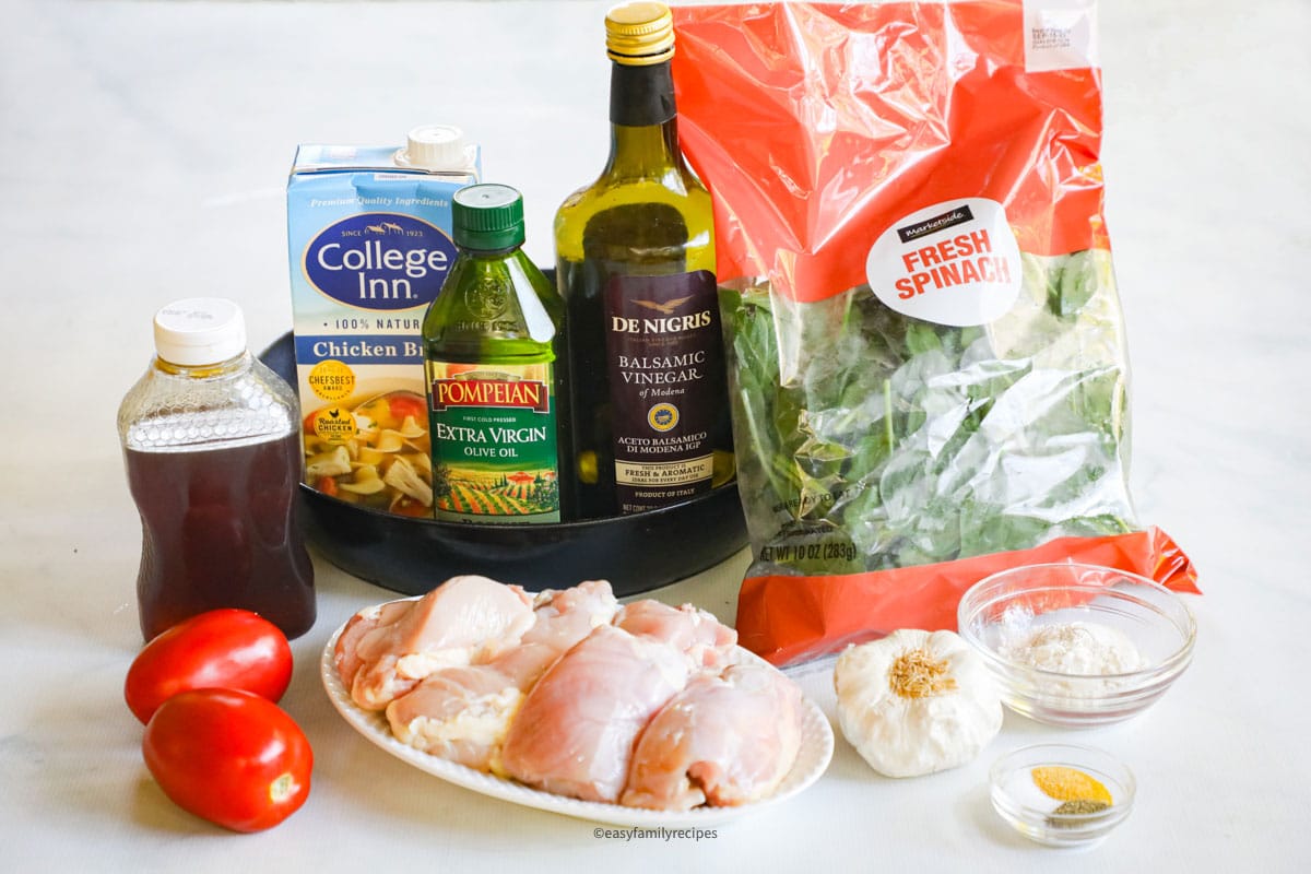 Ingredients for Tuscan chicken thigh skillet, including chicken, garlic, flour, seasonings, honey, oil, spinach, tomatoes, vinegar, and broth