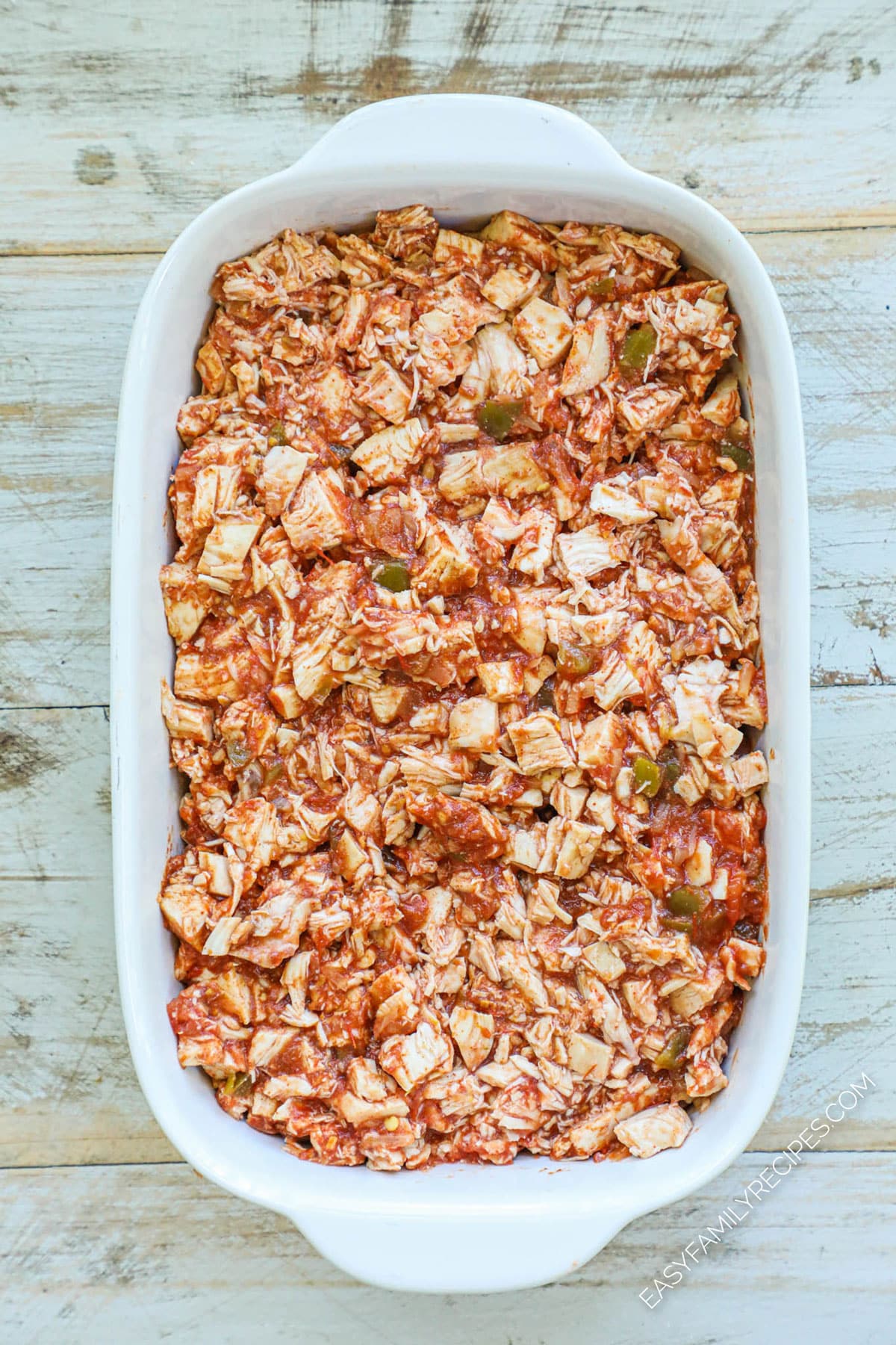 Step 2 How to make chicken taco casserole spread refried beans in a casserole dish then top with taco chicken