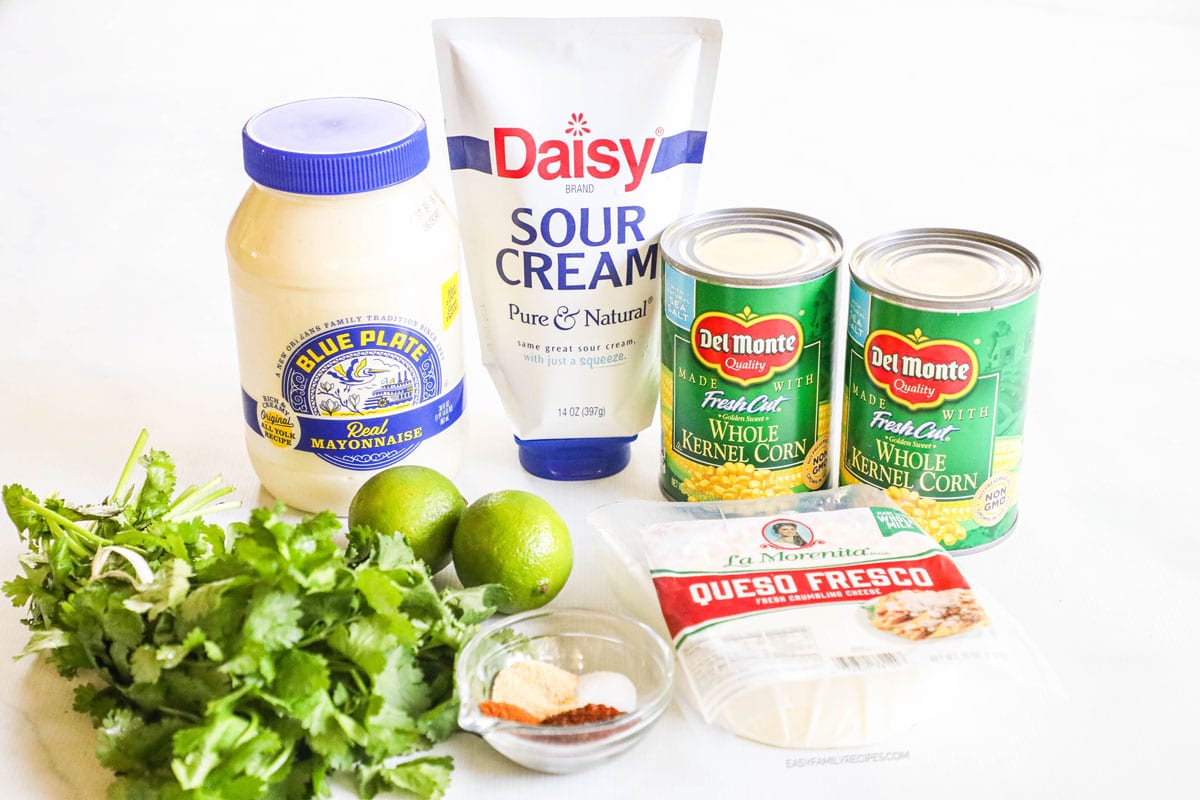 Ingredients for recipe in original containers or whole: cilantro, mayo, sour cream, limes, spices, 2 cans of corn, and queso fresco.