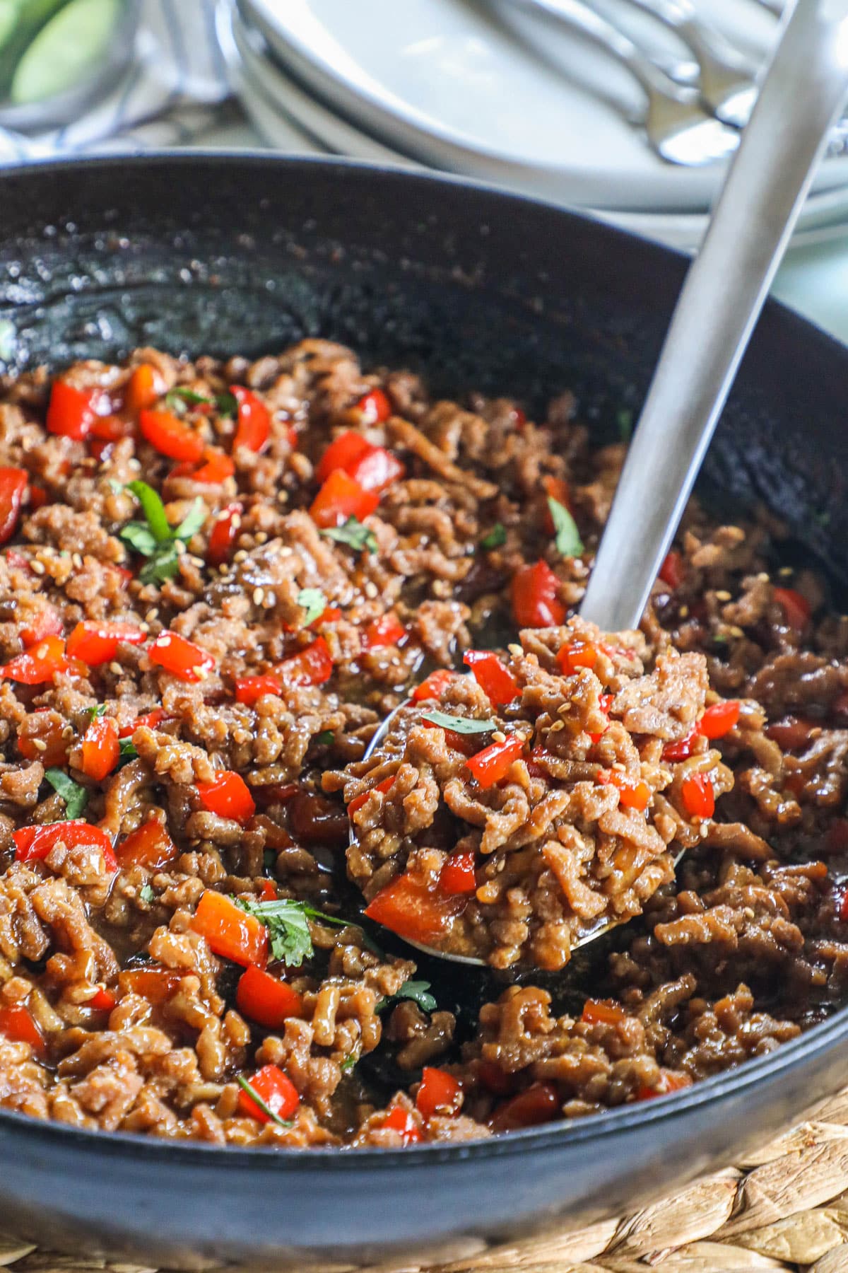 A spoon scooping up a serving of ground turkey teriyaki stir fry from a large pan.
