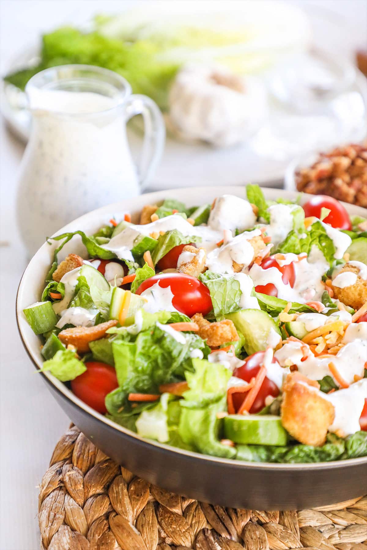 A side salad full of lettuce, tomatoes and croutons with Ranch Dressing