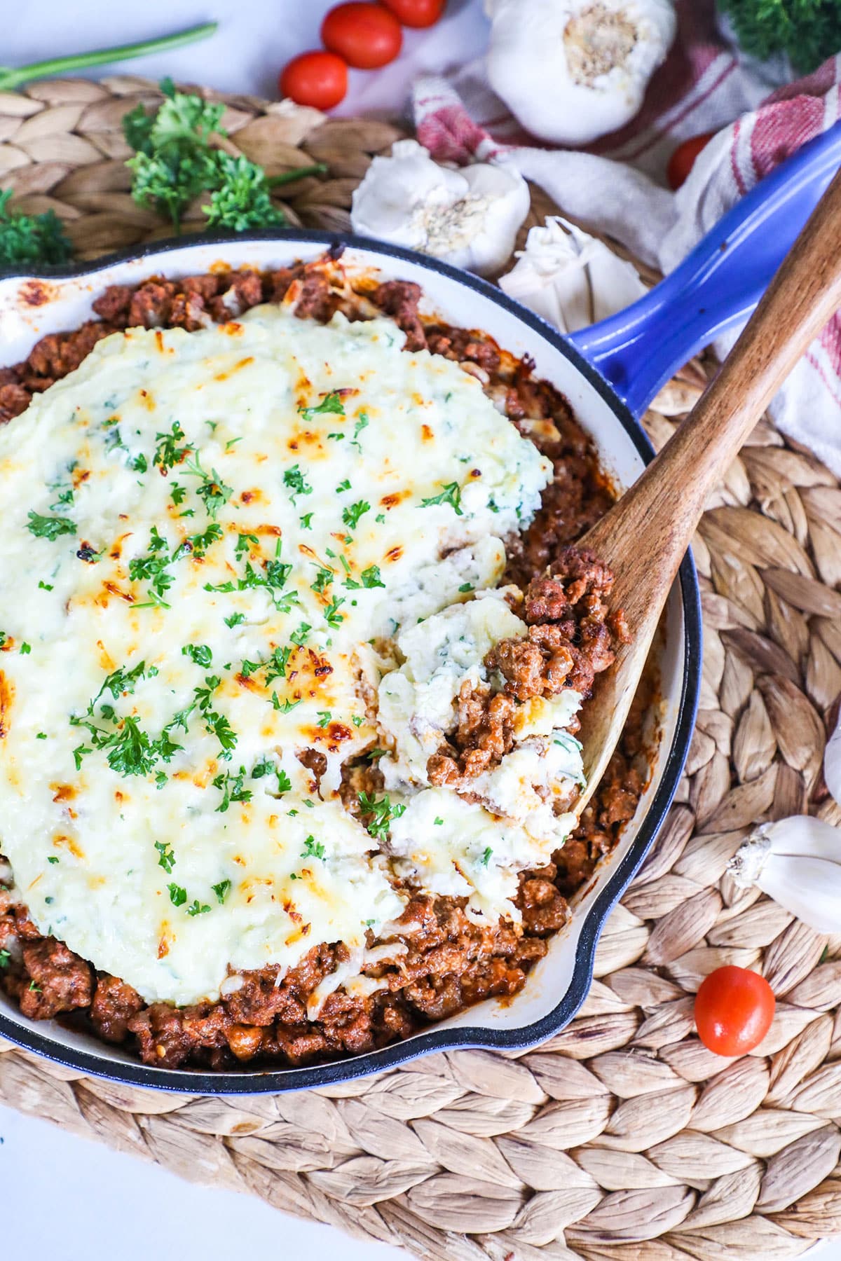 chili lasagna in a blue skillet with a spoon