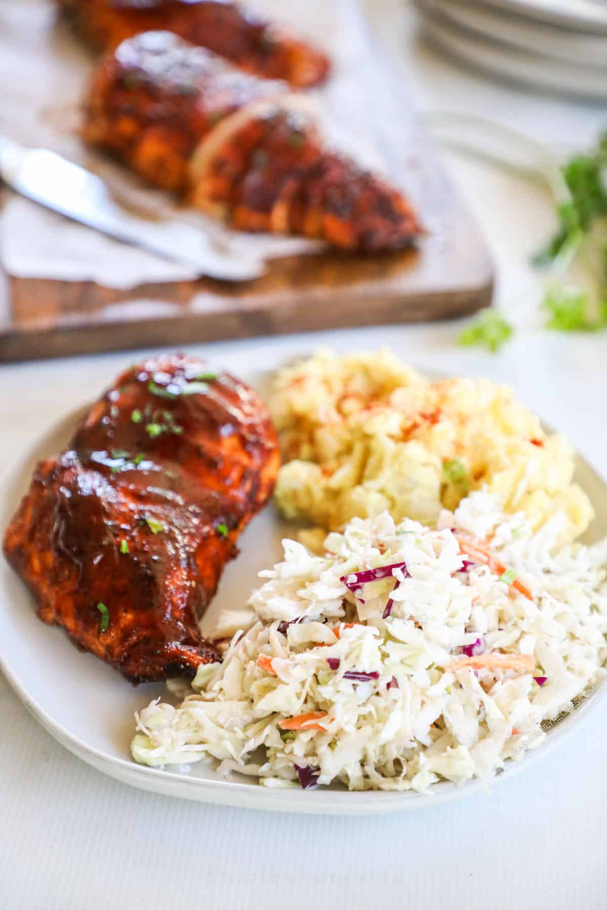 A white plate full of classic BBQ food served up with classic southern coleslaw.