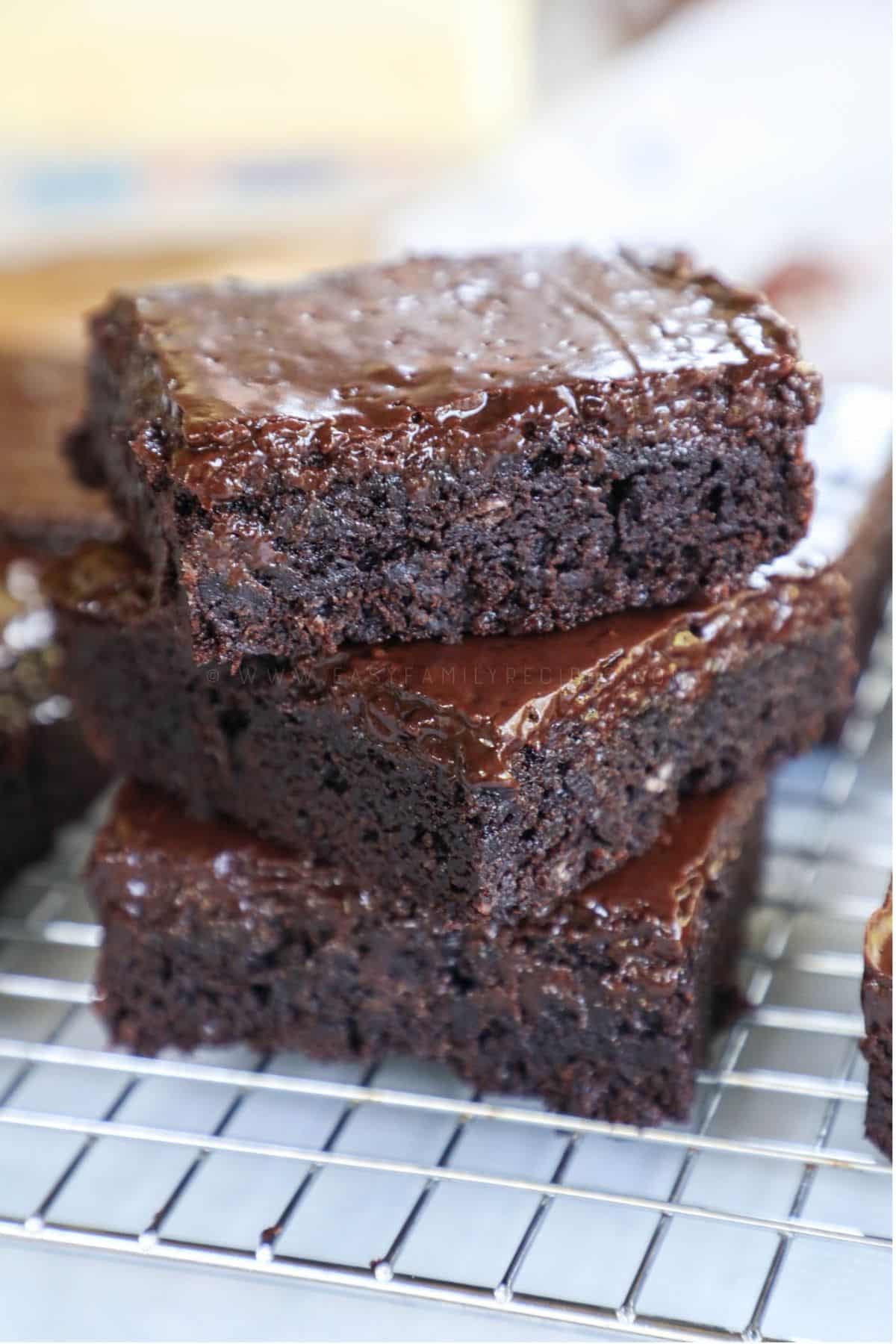 3 fudge brownies stacked on a cooling rack