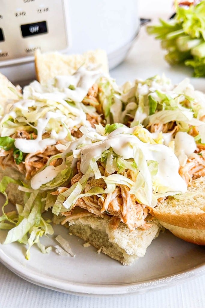 Crockpot Buffalo Sliders on a plate topped with shredded lettuce and ranch dressing.