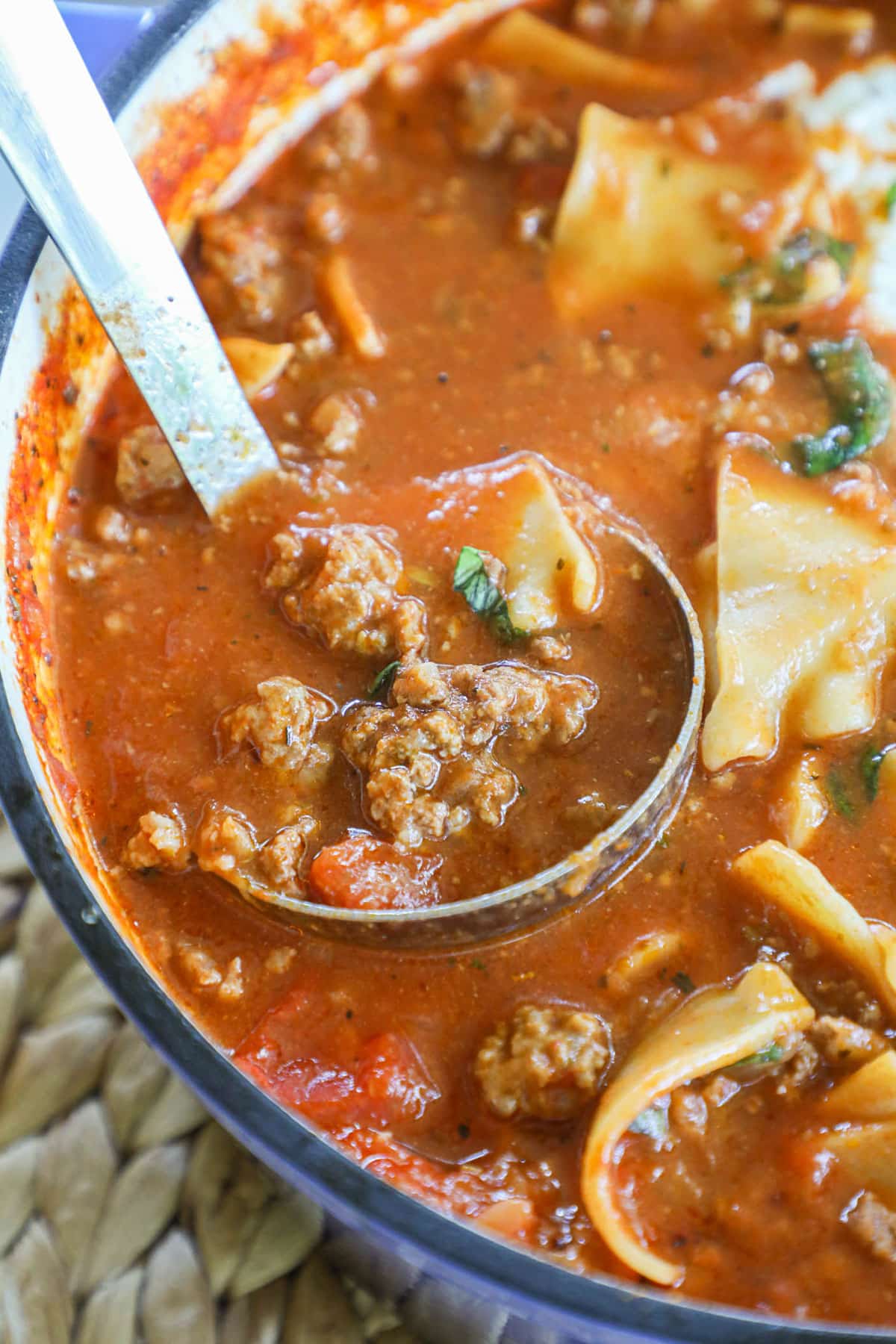 a ladle is scooping lasagna soup out of a pot