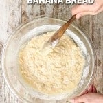 Banana bread batter being mixed in a glass bowl with a wooden spoon. Text on the image reads, "one bowl banana bread."
