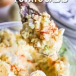 Spoon lifting up a serving of homemade potato salad from a bowl with text "Deviled Egg Potato Salad".
