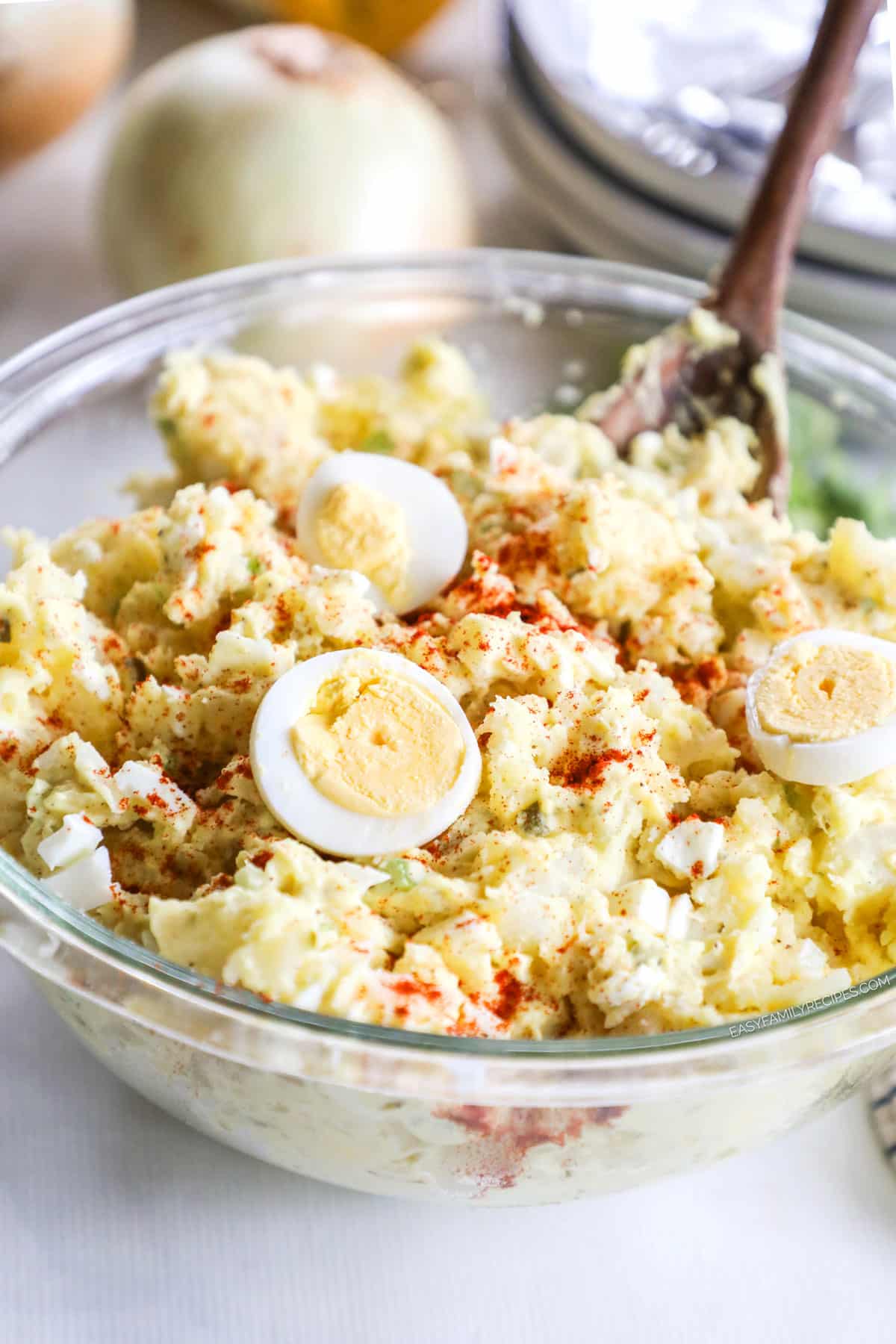 Bowl of devilled egg potato salad with a spoon dipped inside.