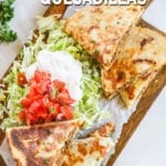 above image of quesadilla slices on a cutting board with toppings.