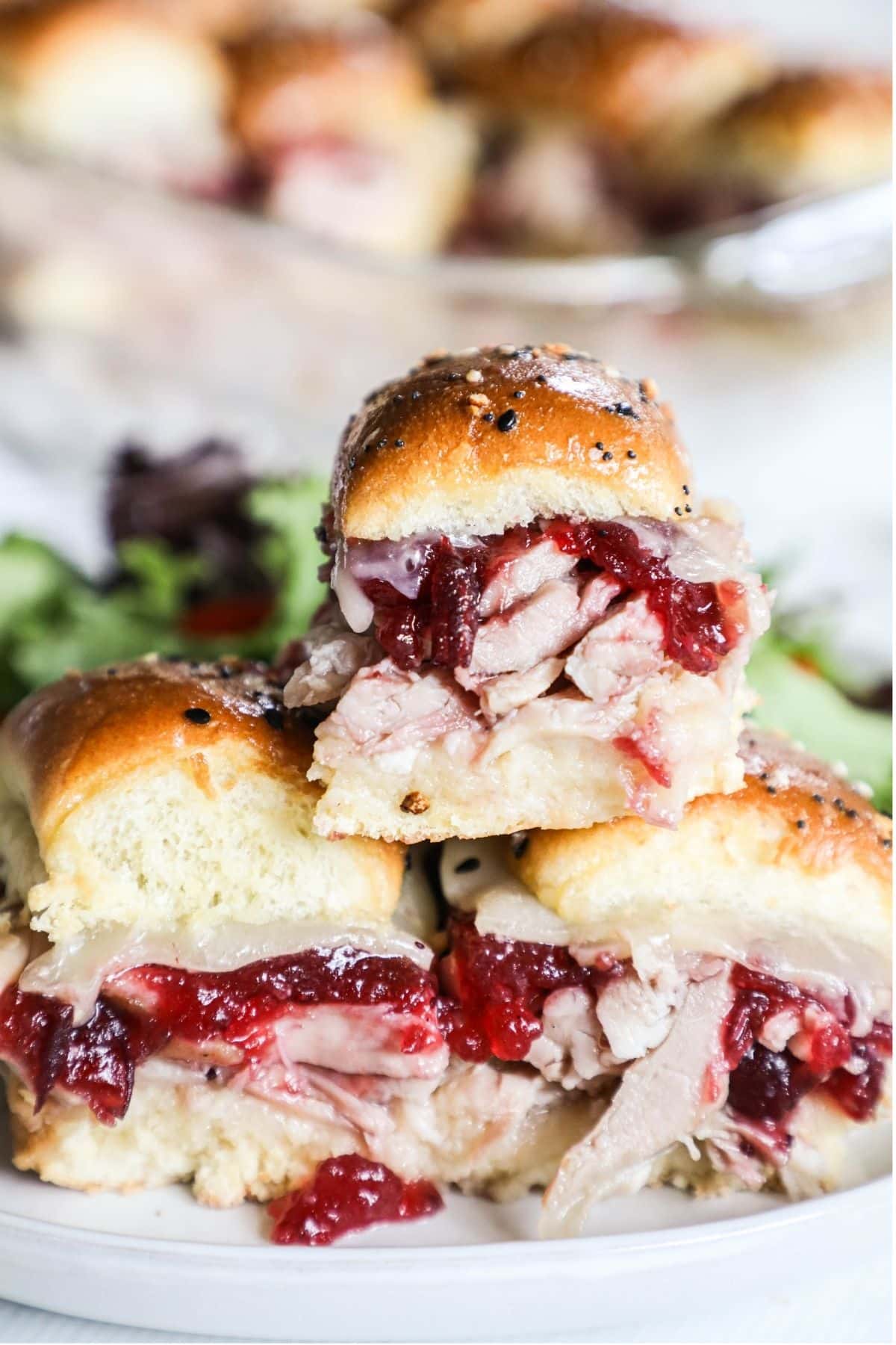 3 ham and cranberry sauce sliders on a plate