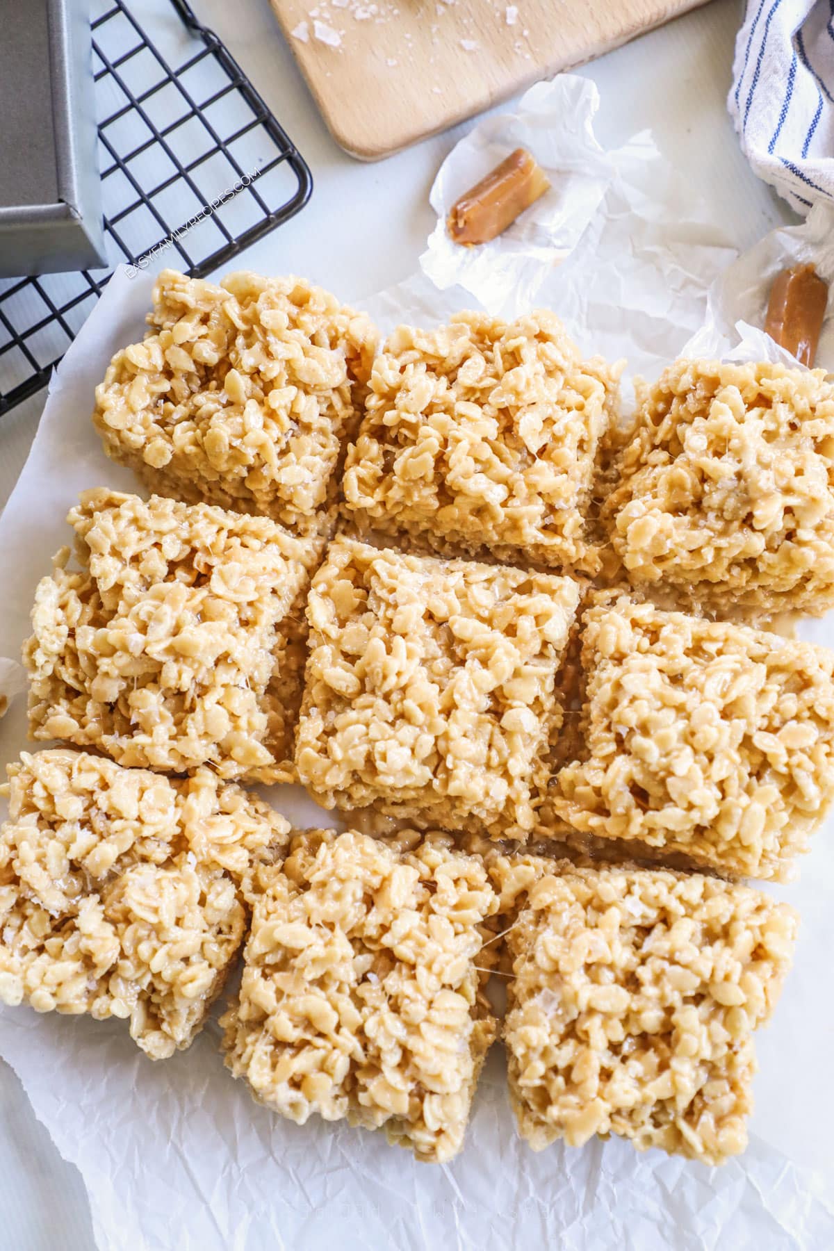 Three rows of salted caramel Rice Krispie treats on a sheet of parchment paper. 