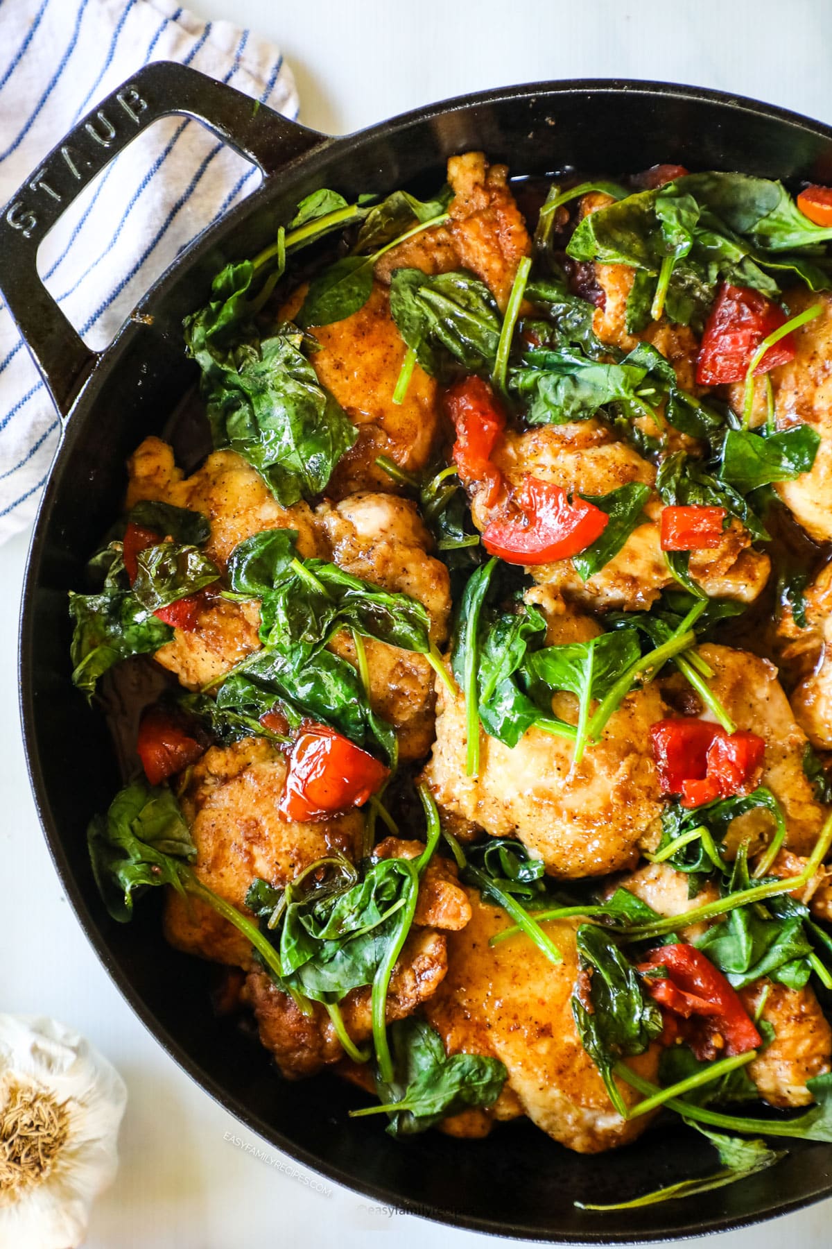 Chicken, tomatoes, wilted spinach in a cast iron skillet 