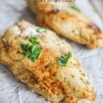 Two Baja Chicken breasts on a piece of parchment paper with herb and jalapeño garnish. The text reads "Baja Chicken."