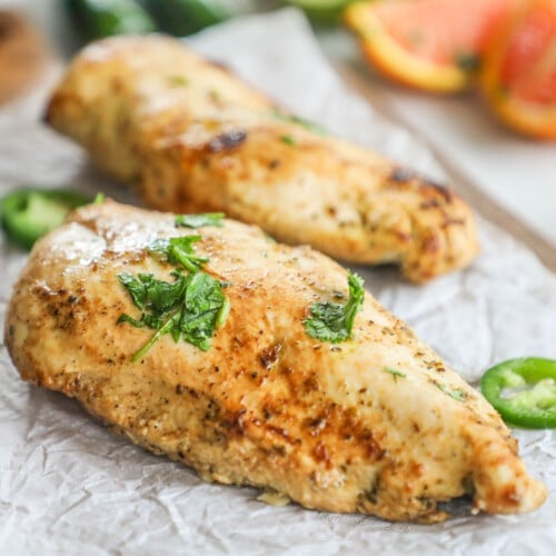 two Baja Chicken breasts with herbs and jalapeño slices.