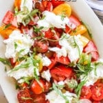 above imge of fresh tomatoes topped with basil and burrata.