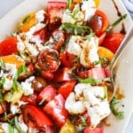 closeup above image of fresh tomato topped with cheese and basil.