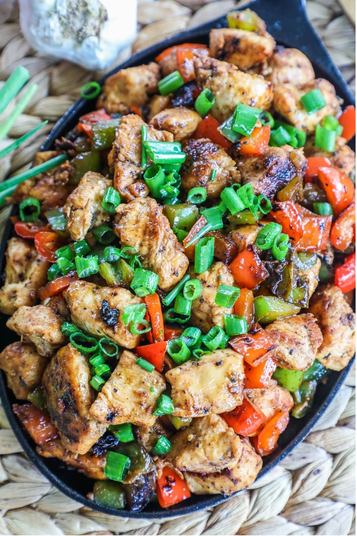 cajun chicken bites with peppers and green onions in a skillet