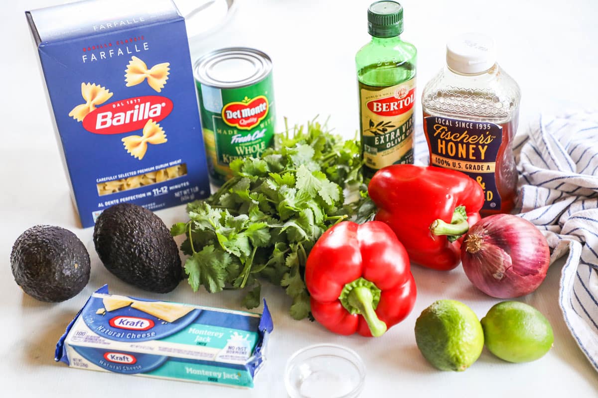 Ingredients to make cilantro lime pasta salad with farfalle including pasta, corn, peppers, cilantro, onions, and honey.