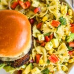 A burger with a generous portion of cilantro lime pasta salad on a plate.