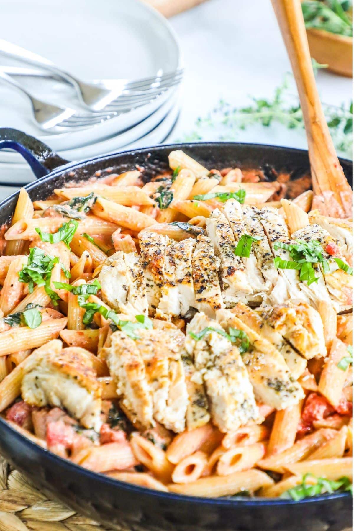 tomato basil pasta in a skillet topped with chicken cutlet slices