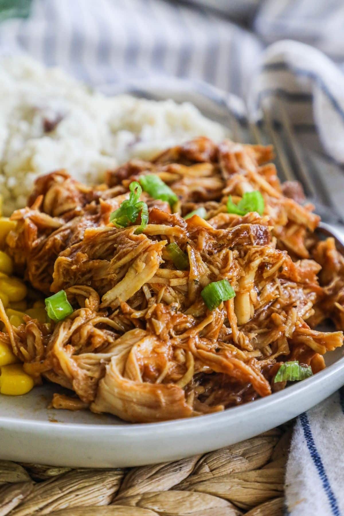 pulled crockpot BBQ chicken on a plate topped with green onions