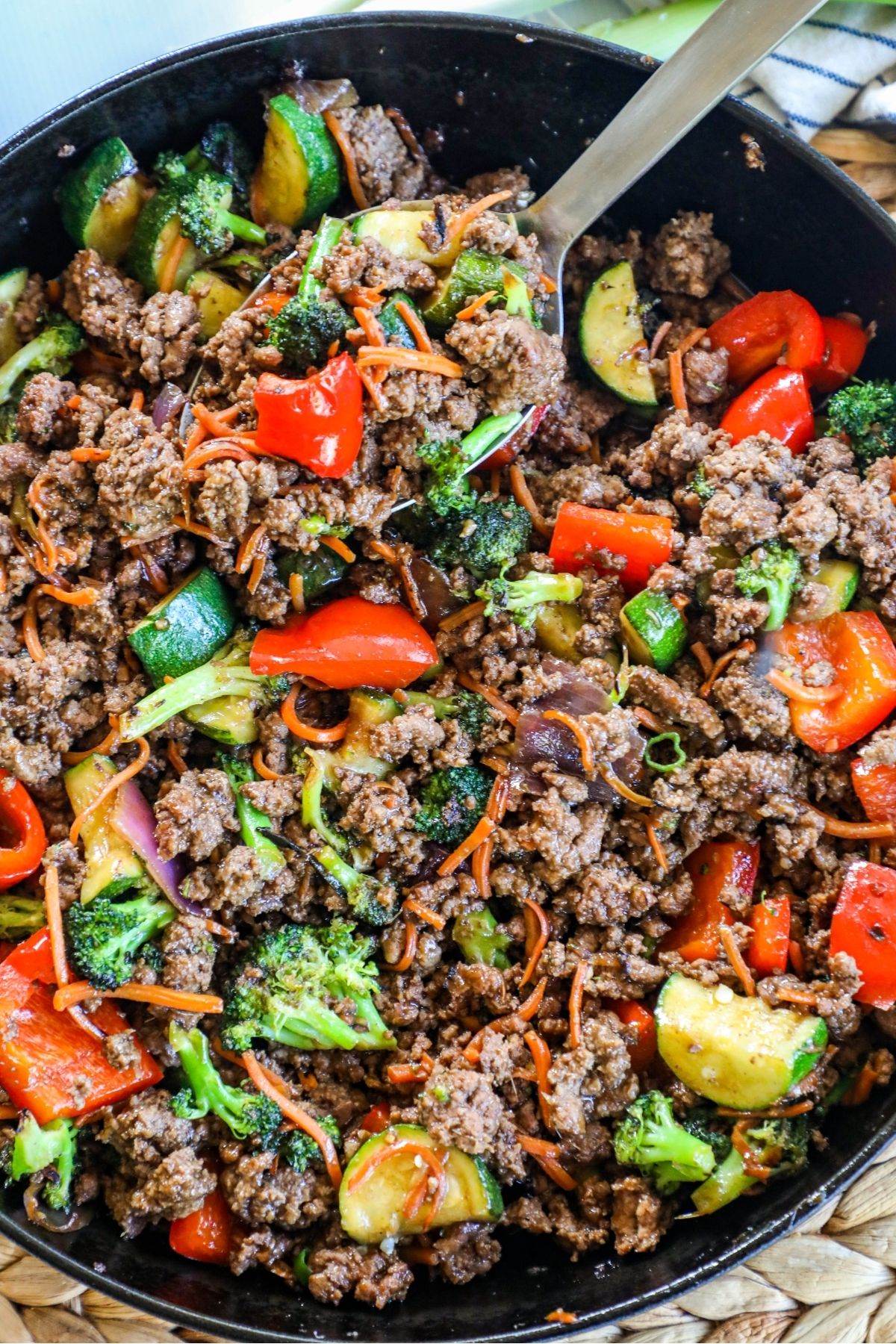 ground beef with peppers and zucchini in a skillet; spoon lifting a scoop