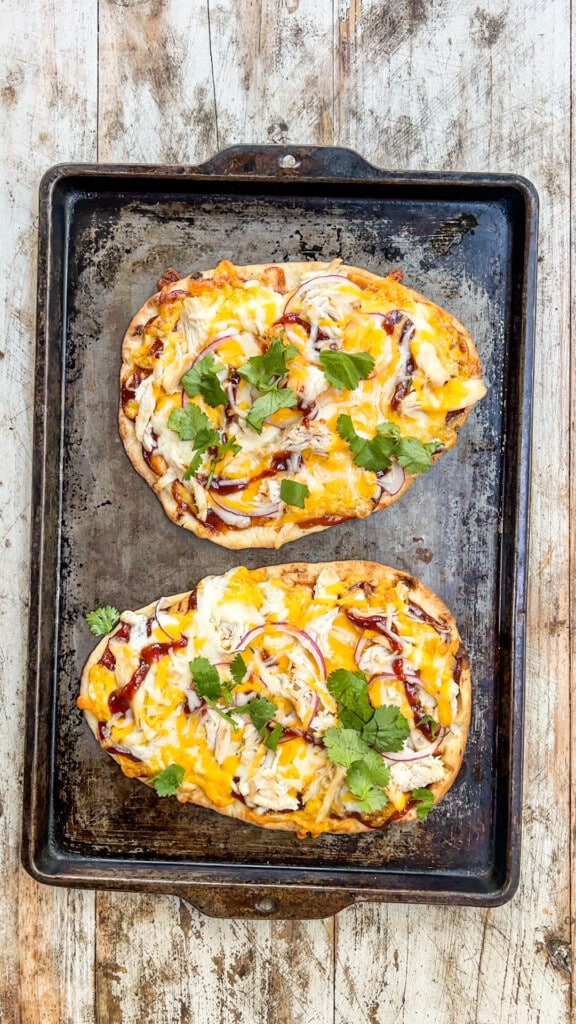 above image of two baked BBQ chicken flatbread pizzas on a baking sheet.