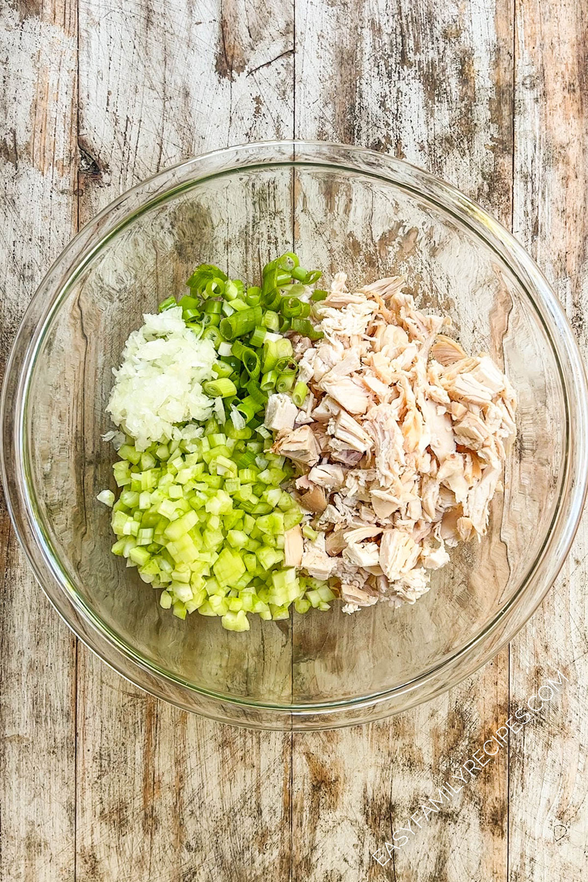Ingredients for buffalo chicken salad in a glass bowl.