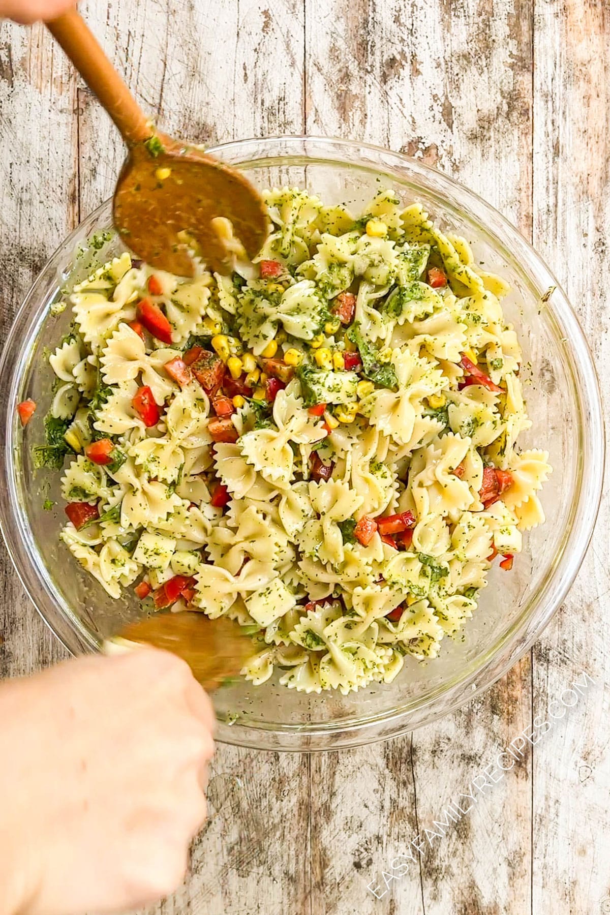 wooden spoons tossing a pasta salad with cilantro lime dressing.