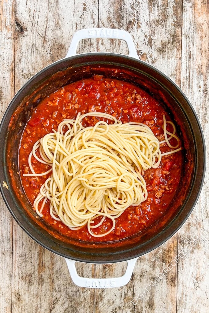 Spaghetti sauce after cooking with cooked noodles added on top.