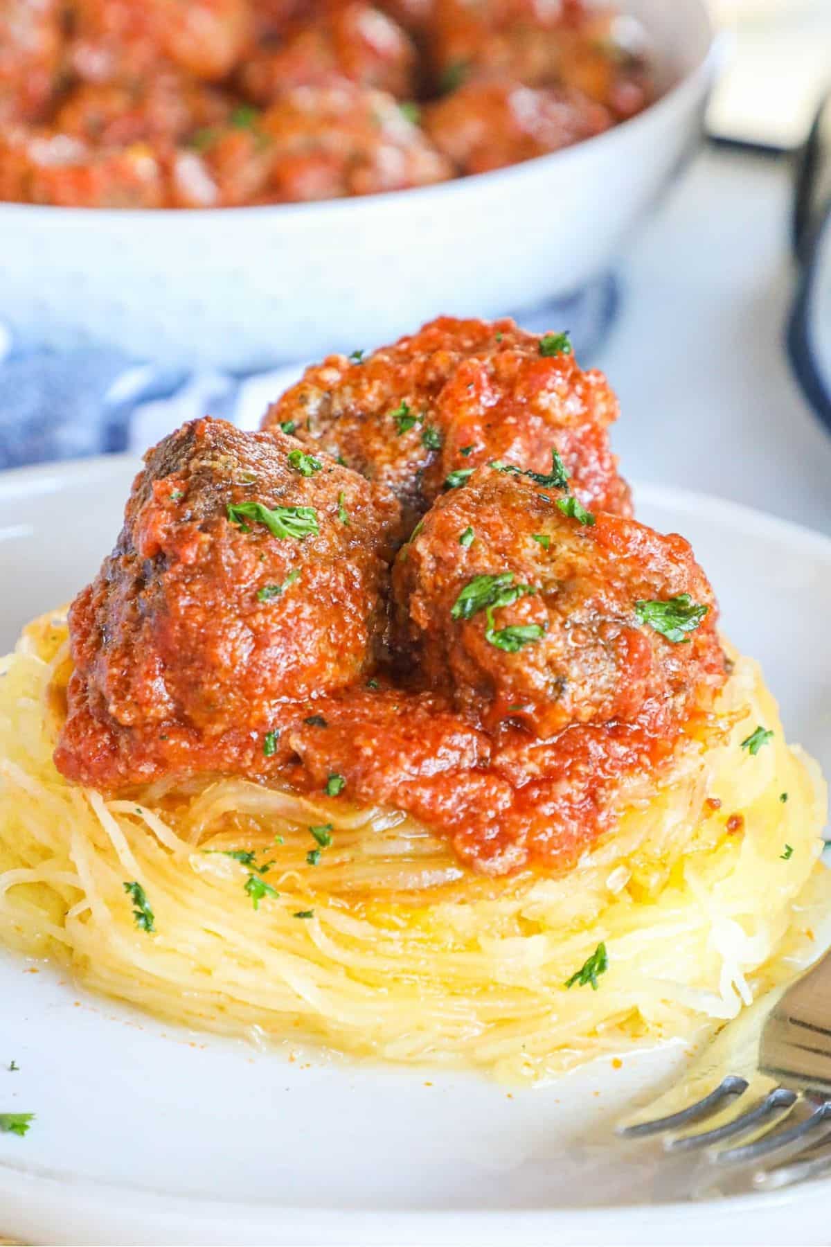 white plate with spaghetti squash topped with meatballs in tomato sauce