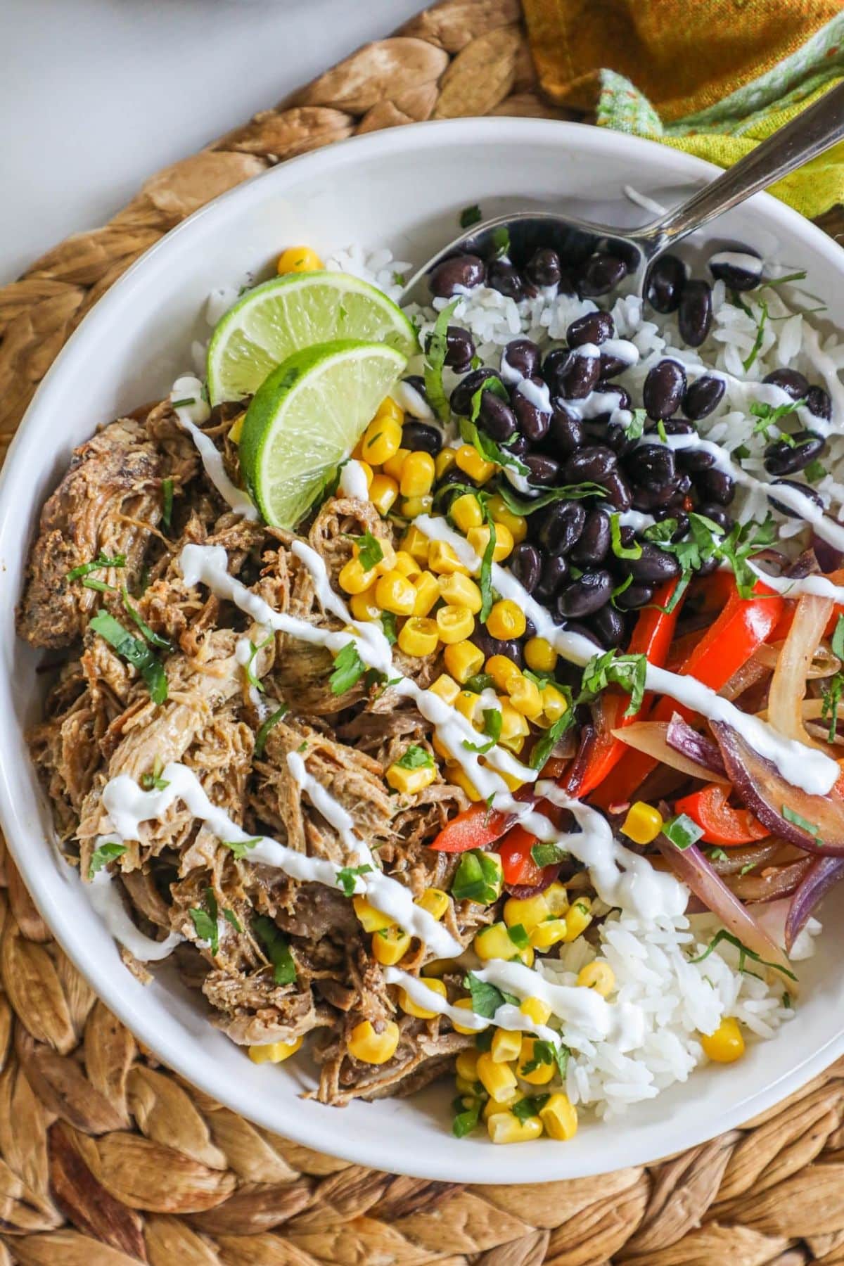 pork bowl with corn, black beans, peppers and lime in a white bowl