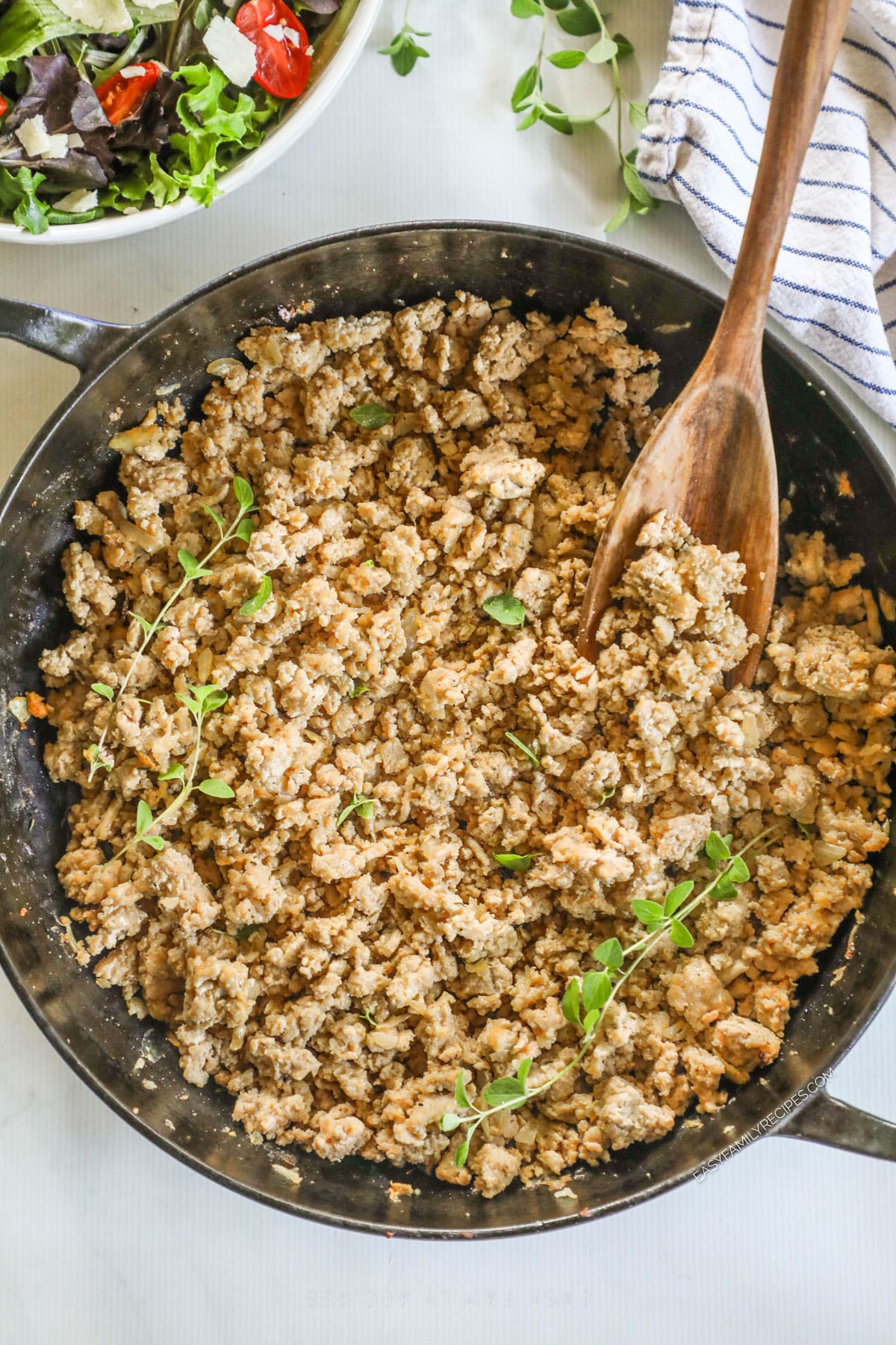 Seasoned ground chicken in a skillet with spoon.