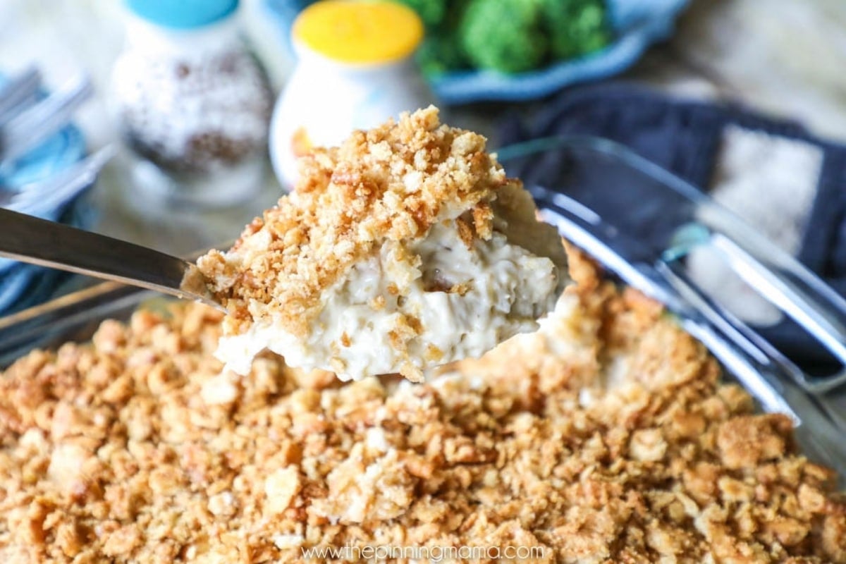 Scooping creamy chicken rice casserole topped with ritz cracker crumb topping out of casserole dish.