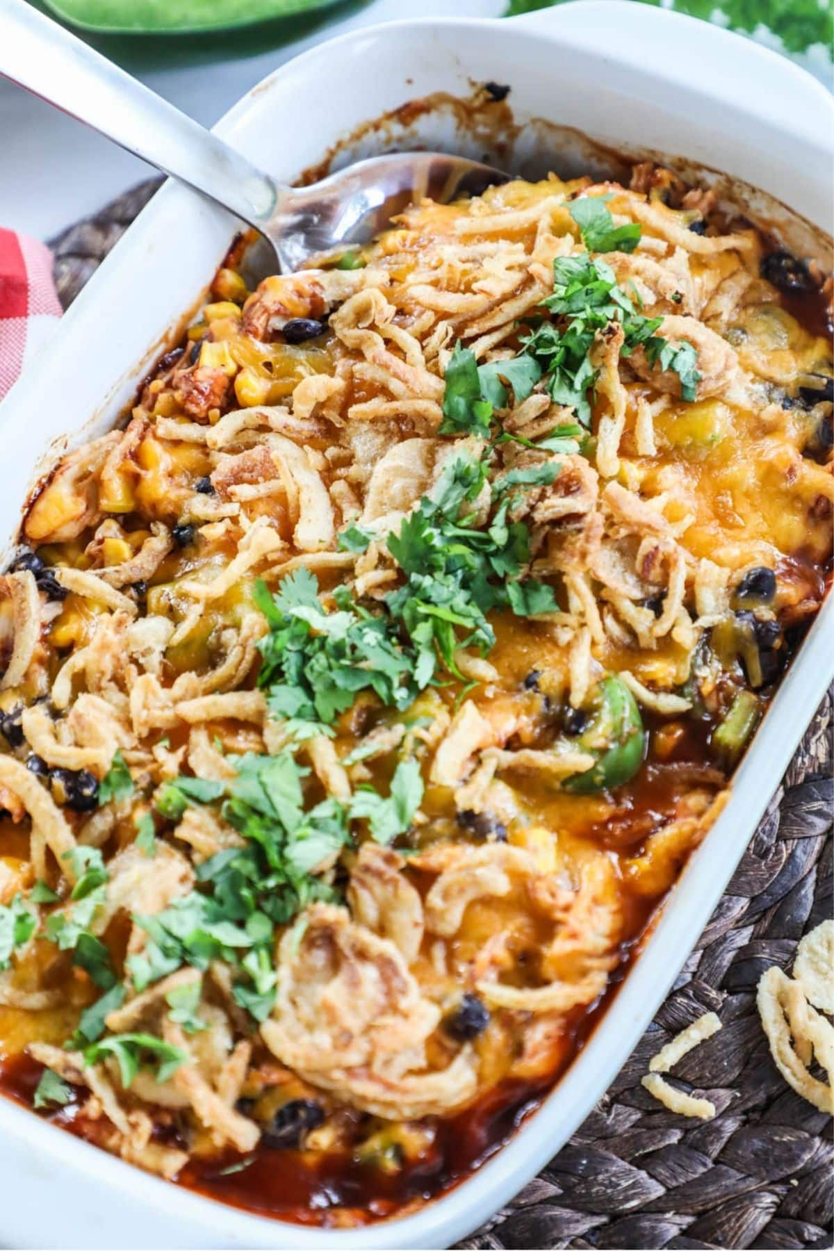 shredded bbq chicken casserole topped with crispy onions and cilantro in a white casserole dish