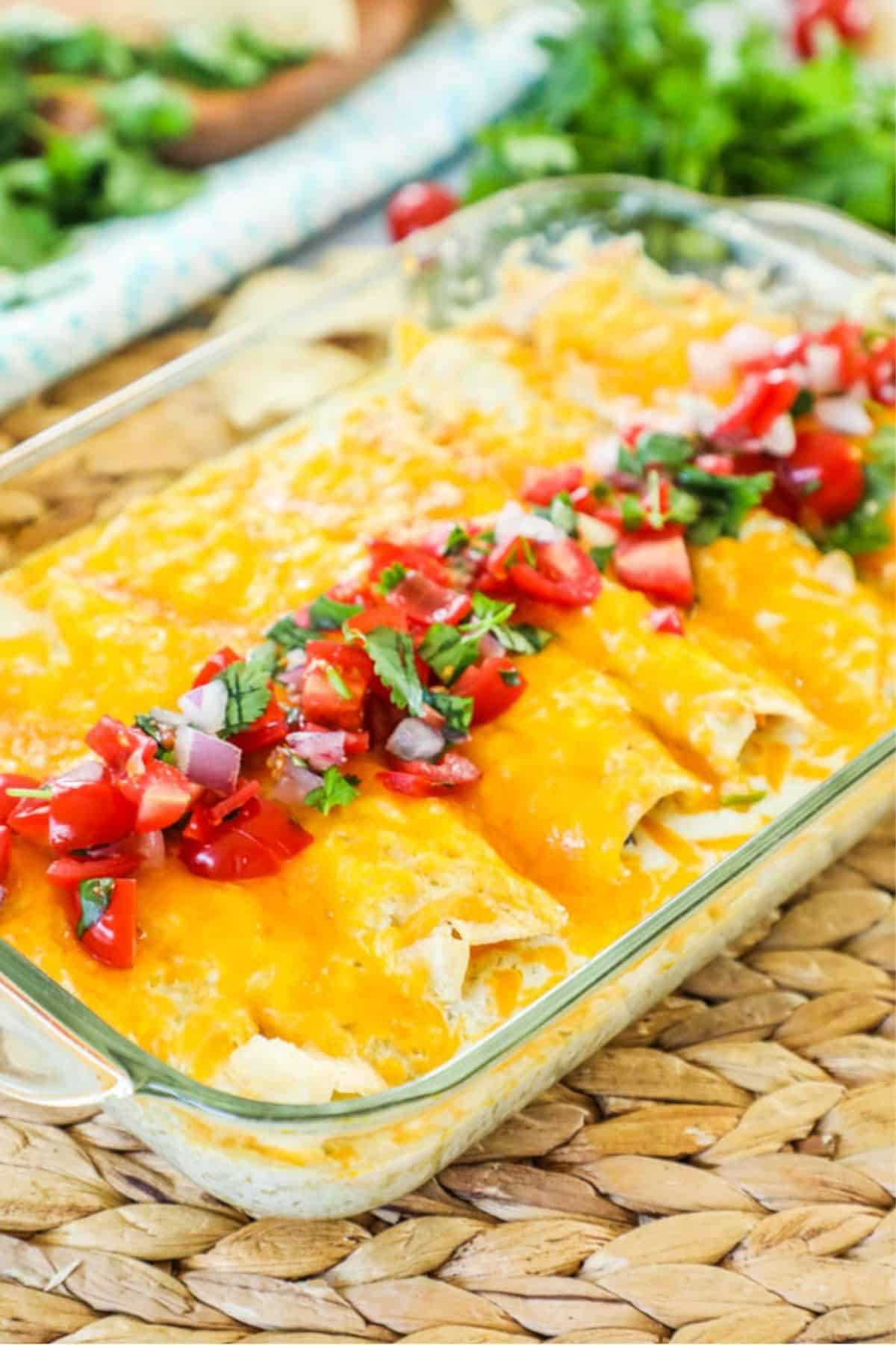 bbq chicken enchiladas covered in cheese and salsa topping in a casserole dish