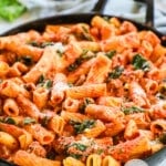a large black cast iron pan full of creamy Italian sausage pasta in a tomato sauce.