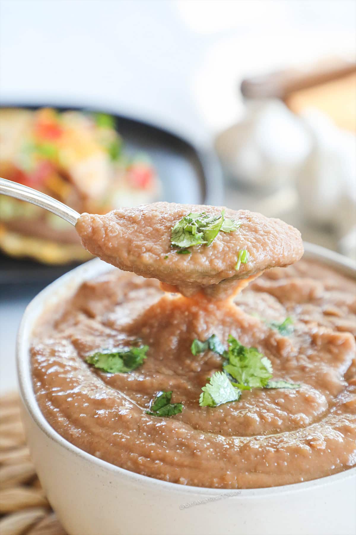 Scooping a spoonful of fresh homemade refried beans from serving bowl.