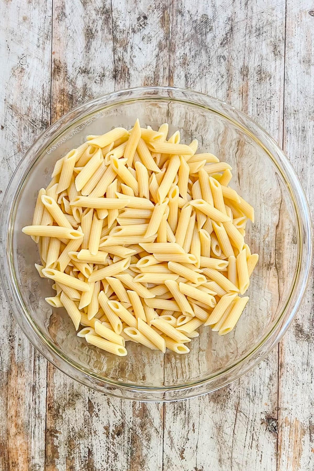 Pasta in a clear glass bowl, ready to be made into Italian Grinder Pasta Salad