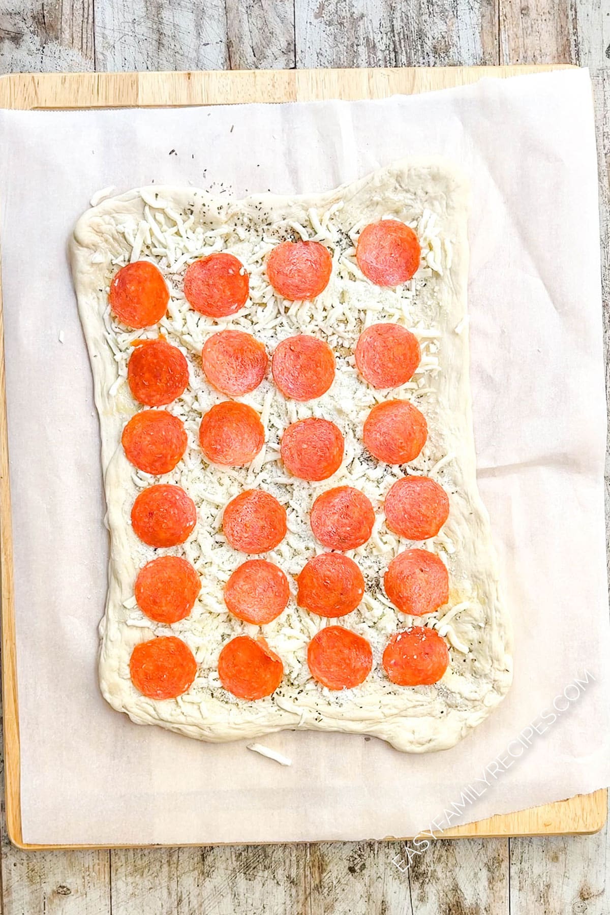 pizza dough topped with cheese and pepperoni.