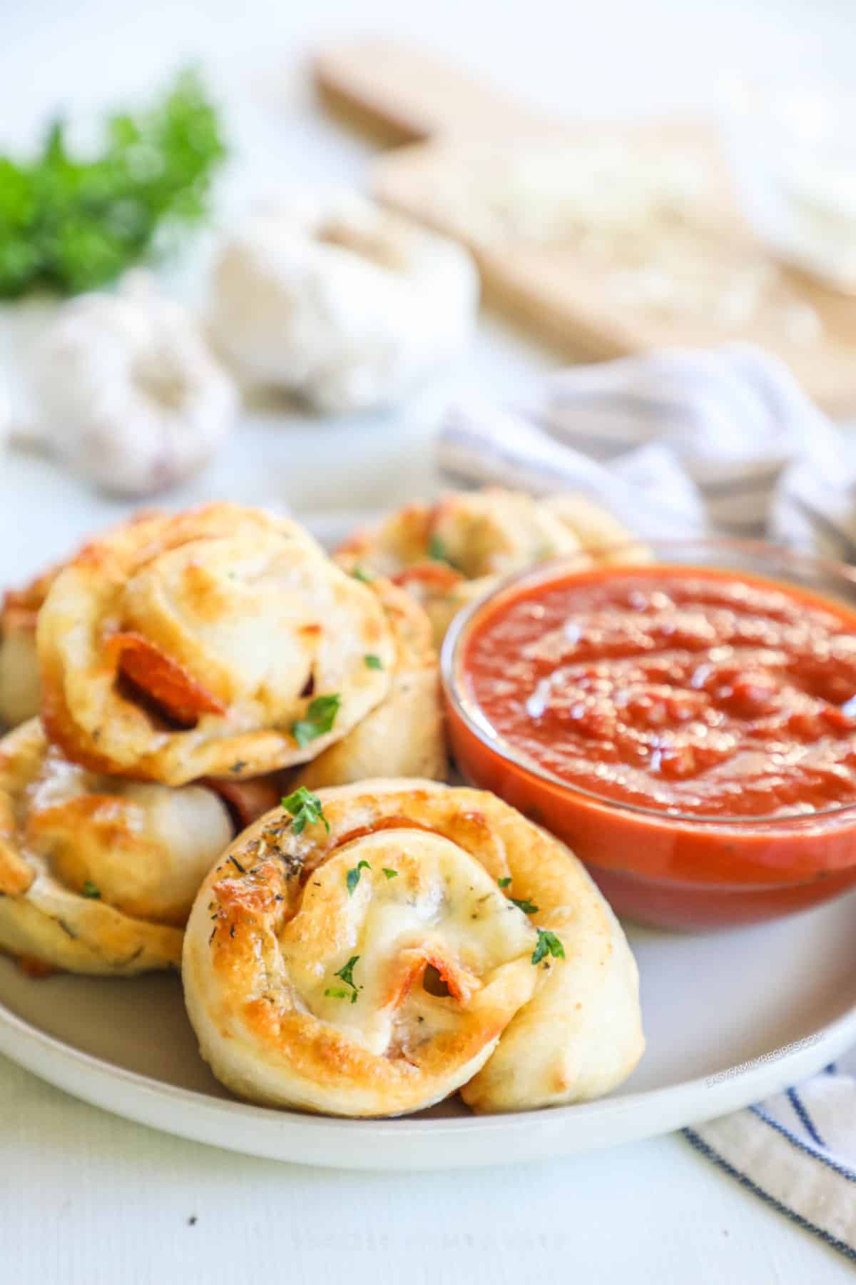 pepperoni pizza rolls on a plate with a small bowl of marinara sauce.
