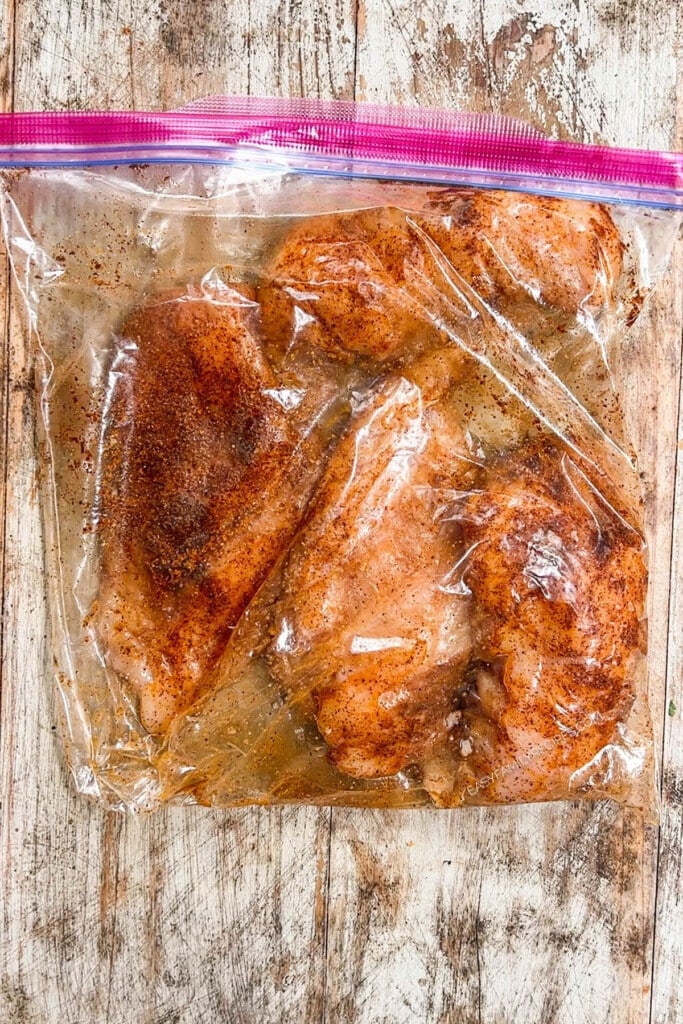 chicken breast being marinated in a ziplock bag.