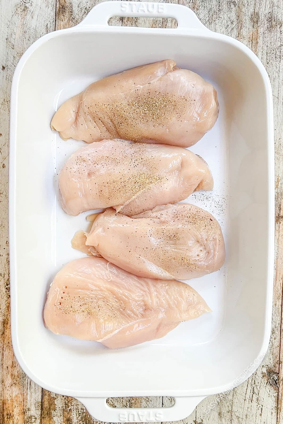 Four chicken breasts are lined up in a baking pan for cheesy bacon ranch chicken bake