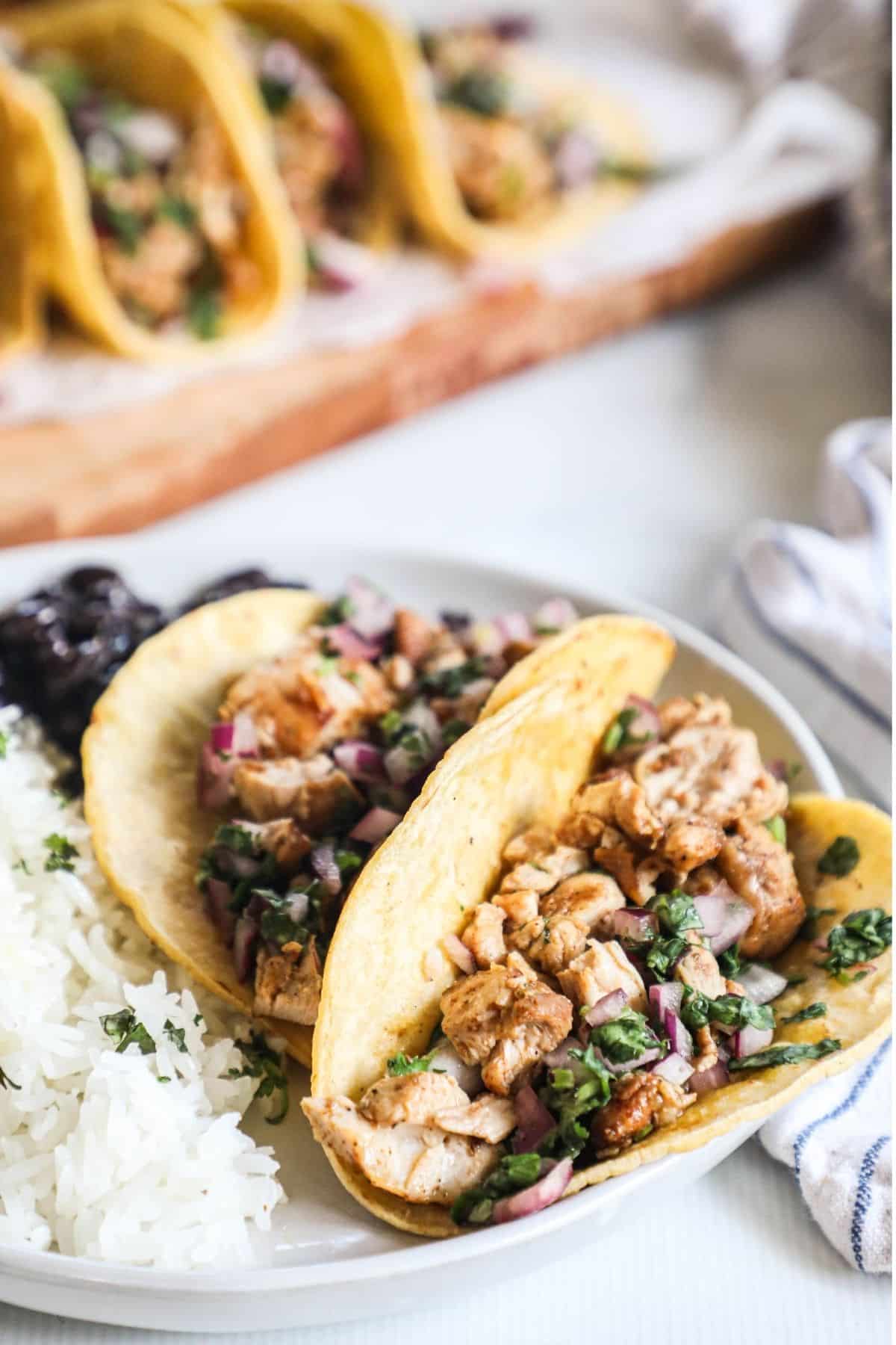2 street tacos on a plate with rice and black beans