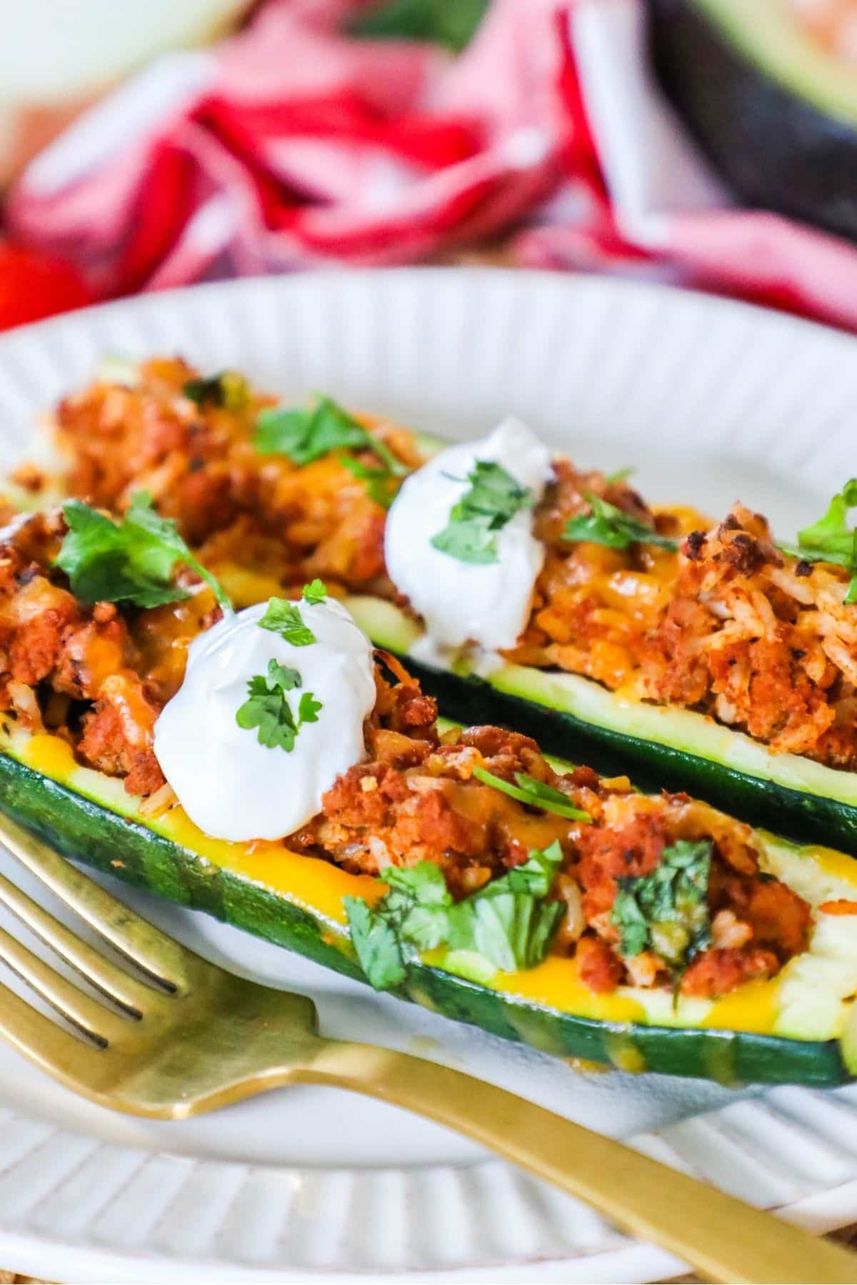 2 zucchini boats on a plate topped with sour cream and cilantro