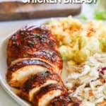 a sliced bbq chicken breast on a plate with coleslaw and potato salad.